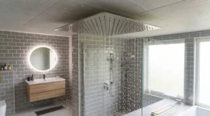 Spacious UK wet room with a high-end ceiling mounted rain shower head, glass screen, and grey metro wall tiles.